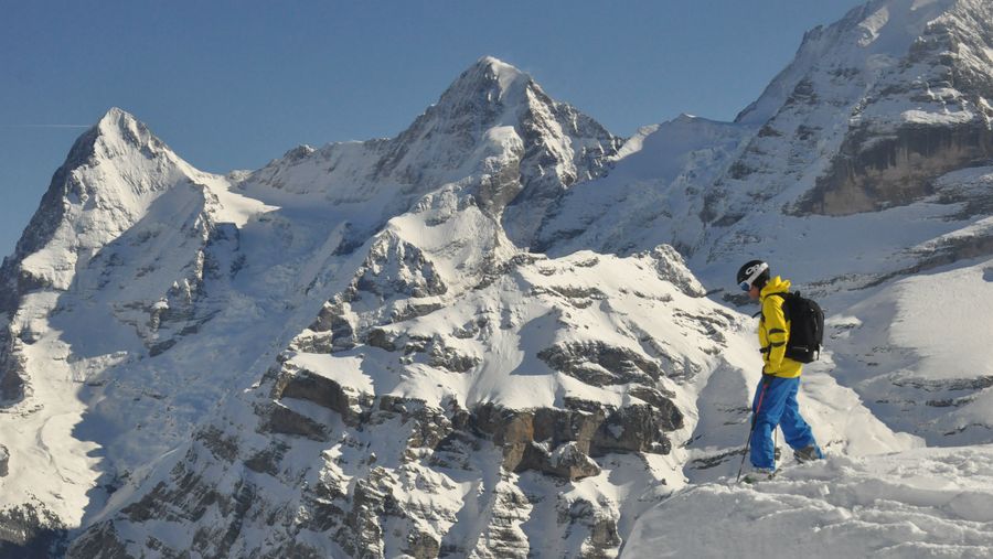 Sifahrer vor der Abfahrt druch den Tiefschnee mit Blick auf die Berge Eiger und Mönch