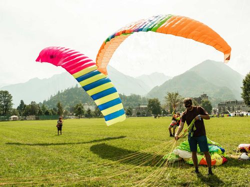 Teilnahmende des Jubiläumsanlasses 50 Jahre Schweizerischer Hängegleiterverband lassen nostalgische Gleitschirme im Wind aufsteigen