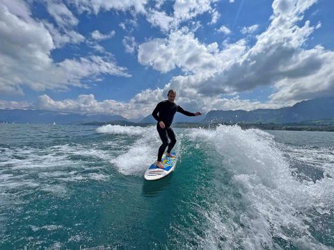Ein Surfer im Neoprenanzug nimmt lässig eine Welle auf dem Thunsersee