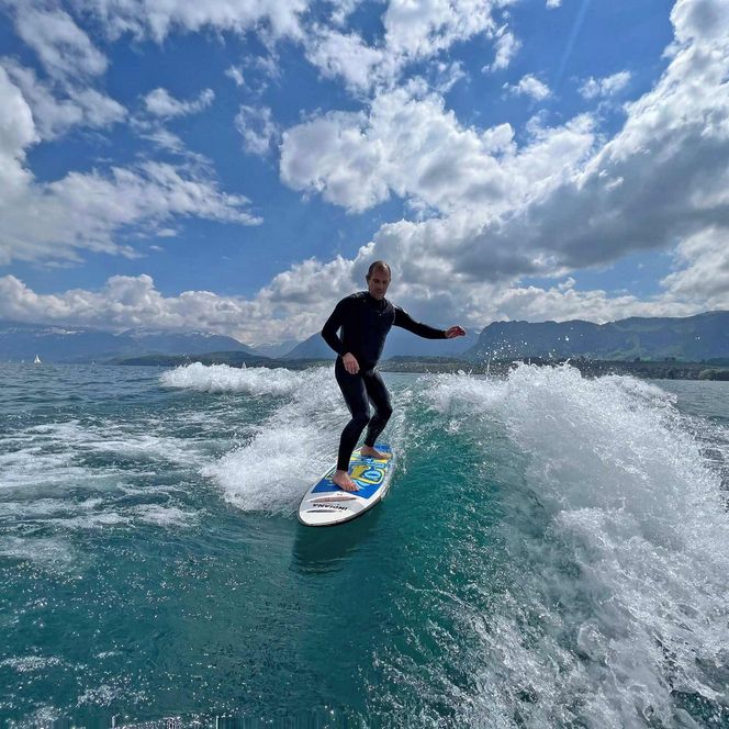 Ein Surfer im Neoprenanzug nimmt lässig eine Welle auf dem Thunsersee