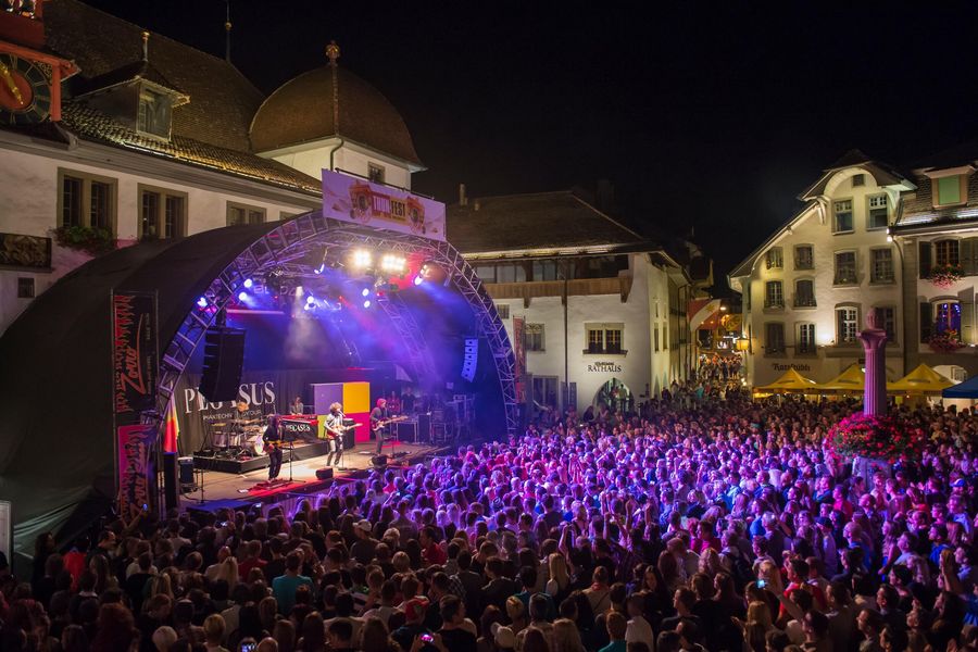 Bühne mit violetter Beleuchtung und Zuschauer auf dem Rathausplatz in Thun