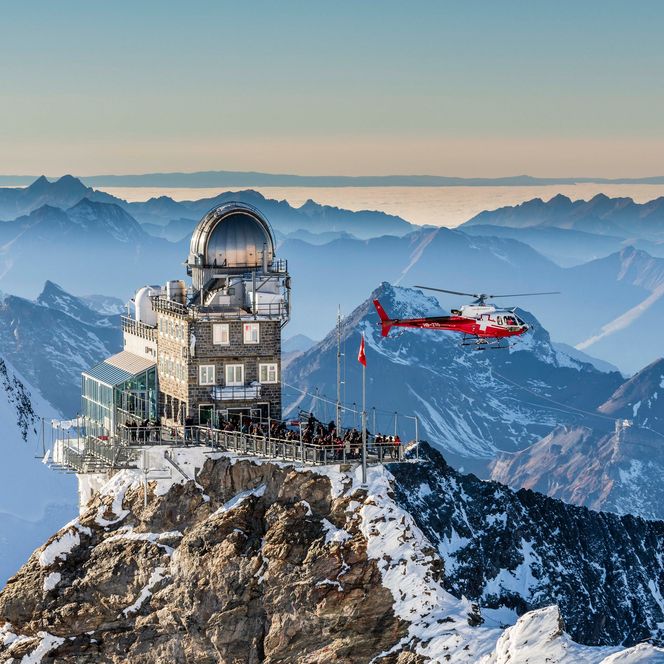 Die Station auf dem Jungfraujoch erhebt sich majestätisch auf dem Bergrücken und wird von einem Helikopter umflogen.