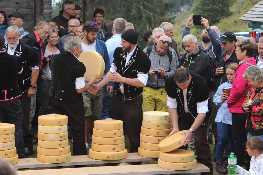 Käse wird von Älplern auf Holzbrettern aufgetürmt umgeben von Zuschauern