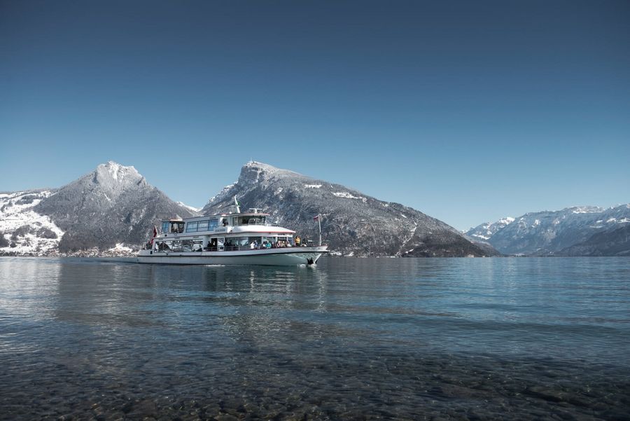 Schiff auf dem blauen Thunersee mit verschneitem Niederhorn im Hintergrund