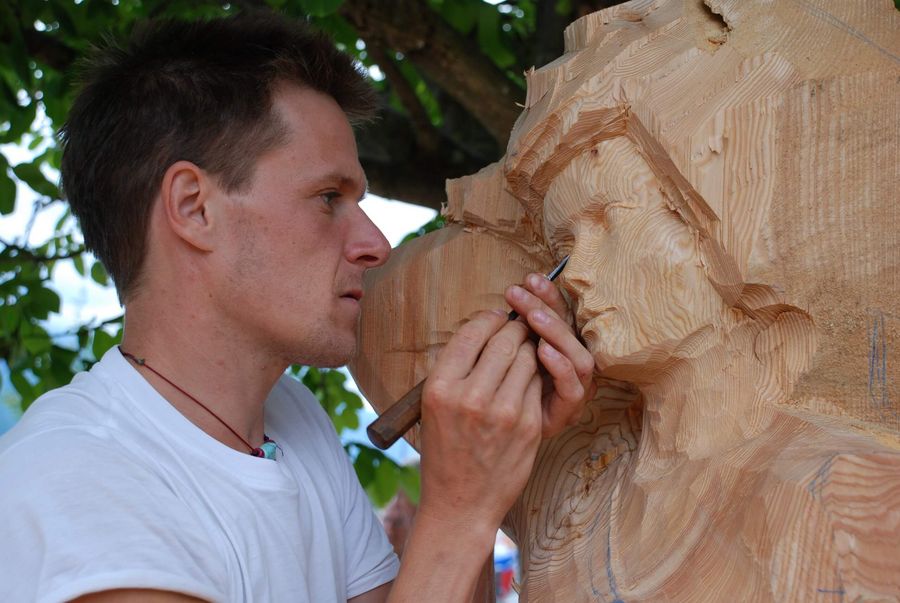 Ein Holzbildhauer schnitzt an seiner Skulptur am Holzbildhauer Symposium in Brienz