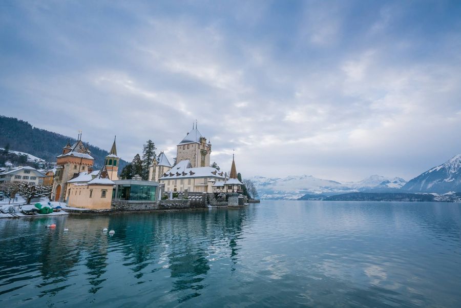 Schloss Oberhofen sanft verschneit im Wintermood am spiegelglatten Thunersee