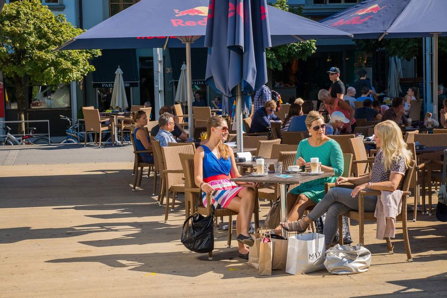 Freundinnen geniessen nach einer Shoppingtour die Sommersonne auf dem Mühleplatz in Thun