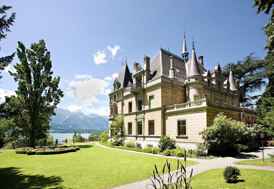 Schloss Hüngee in Hilterfingen mit grüner Wiese und Thunersee im Hintergrund