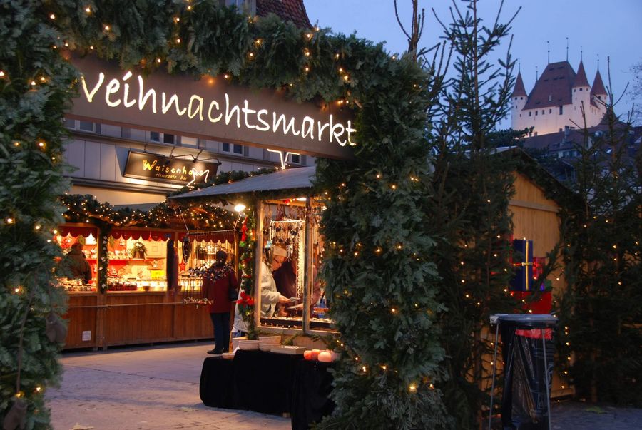 Festlich beleuchtete Weihnachtsmarktstände laden in Thun vor der Kulisse des Schlosses zum Geniessen und Durchschlendern ein. 