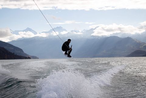 Ein Wakeboarder vollzieht einen Sprung vor der Bergkulisse des Thunersees. 