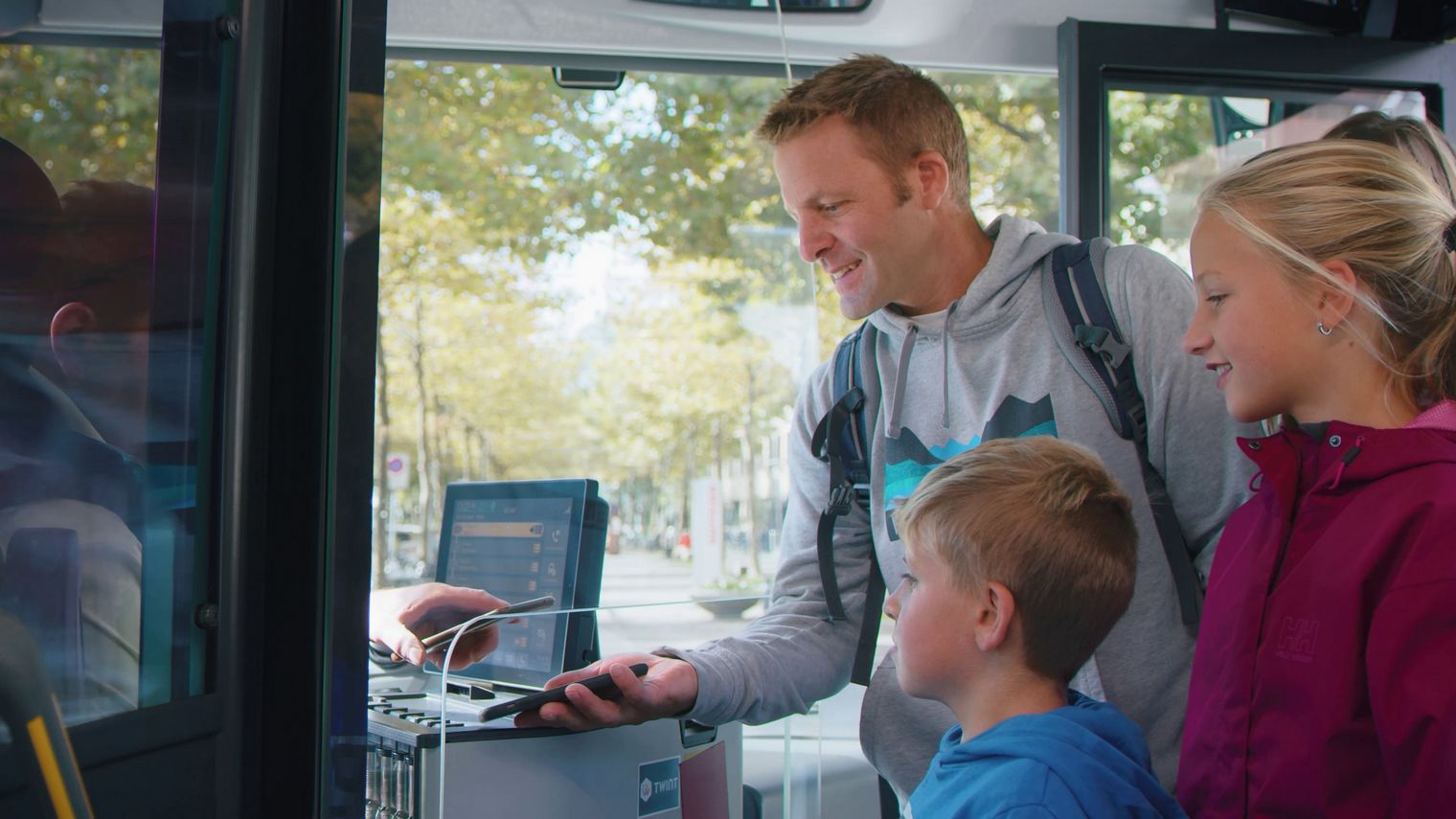 Familienvater in Begleitung seiner Kinder und seiner Frau lässt seinen Interlaken Pass vom PostAuto-Fahrer einscannen.