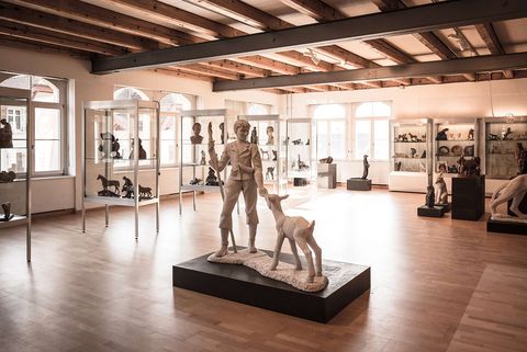 Ausstellungsraum Schweizer Holzbildhauerei Museum in Brienz. Mitten im Bild eine lebensgrosse Skulptur eines jungen Ziegenhiertn mit einer Ziege.