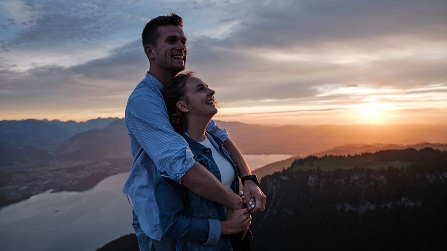 Ein Paar umamt sich und geniesst die Aussicht auf den Thunersee bei Sonnenuntergang.