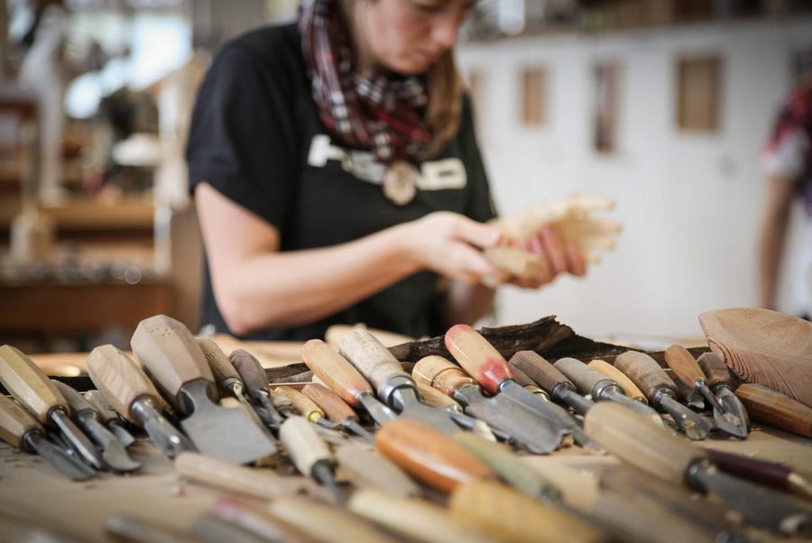 Verschiedene Werkzeuge für die Holzschnitzkunst in der Schule für Holzbildhauerei in Brienz. Im Hintergrund eine Schülerin.