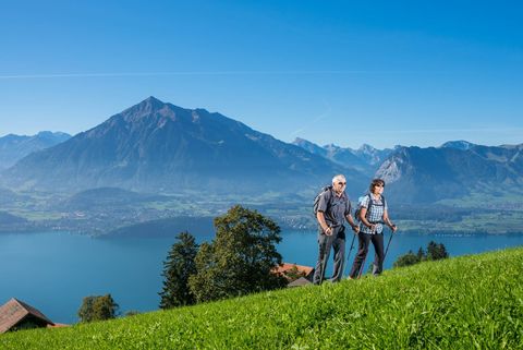Ein älteres Paar auf einer Wanderung oberhalb des Thunersees und mit Blick auf Niesen
