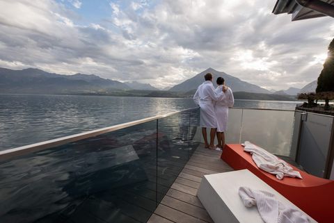 Paar blickt nach dem Spa im Bademantel auf den Thunersee und den Niesen