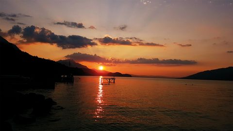 Oranger Sonnenuntergang spiegelt sich im Thunersee in der Badi Leissigen
