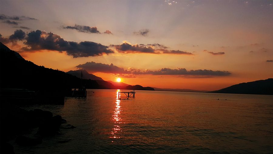 Oranger Sonnenuntergang spiegelt sich im Thunersee in der Badi Leissigen