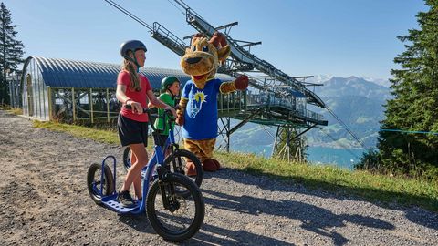 Drei Trotti-Biker mit der Niederhornbahn mit Bergpanorama im Sommer