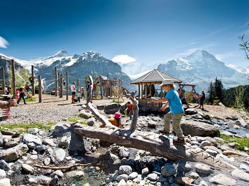 Kinder vergnügen sich auf dem Spielplatz Bort umgeben von Bergen