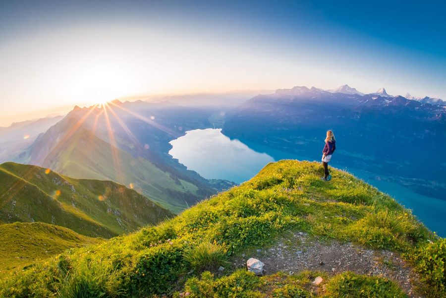 Wanderererin blickt vom Augstmatthorn über den Brienzersee und geniesst den Sonnenaufgang