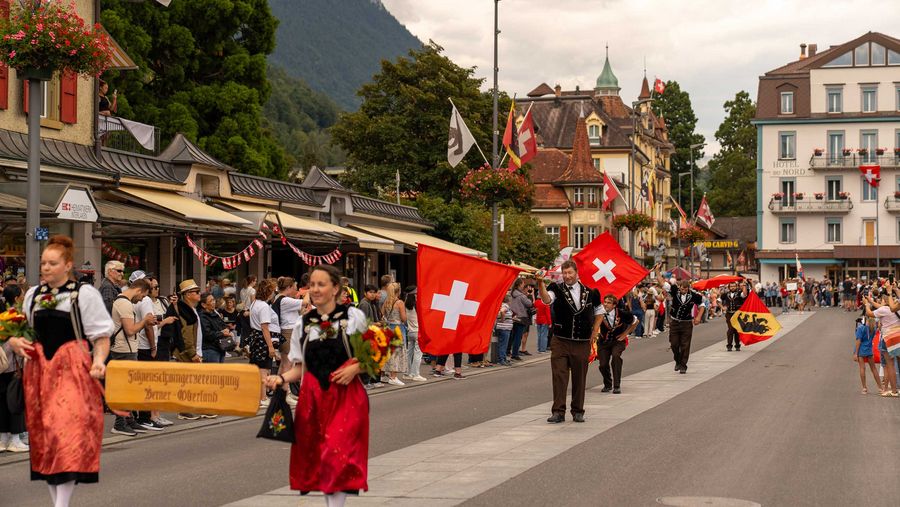 Angeführt von Trachtenfrauen zeigen Fahnenschwinger ihr Können am 1. August Umzug