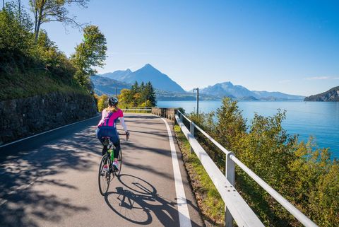 Eine Frau unterwegs am Thunersee mit dem Rennrad auf grauem Asphalt