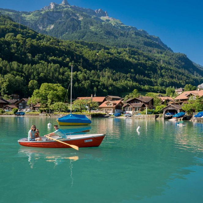 Familie gleitet mit dem Ruderboot in der Bucht bei Iseltwald über den Brienzersee.