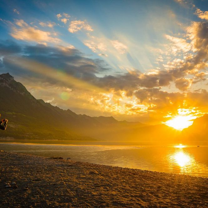 Ein Spaziergänger fotografiert den Sonnenaufgang am Brienzersee.
