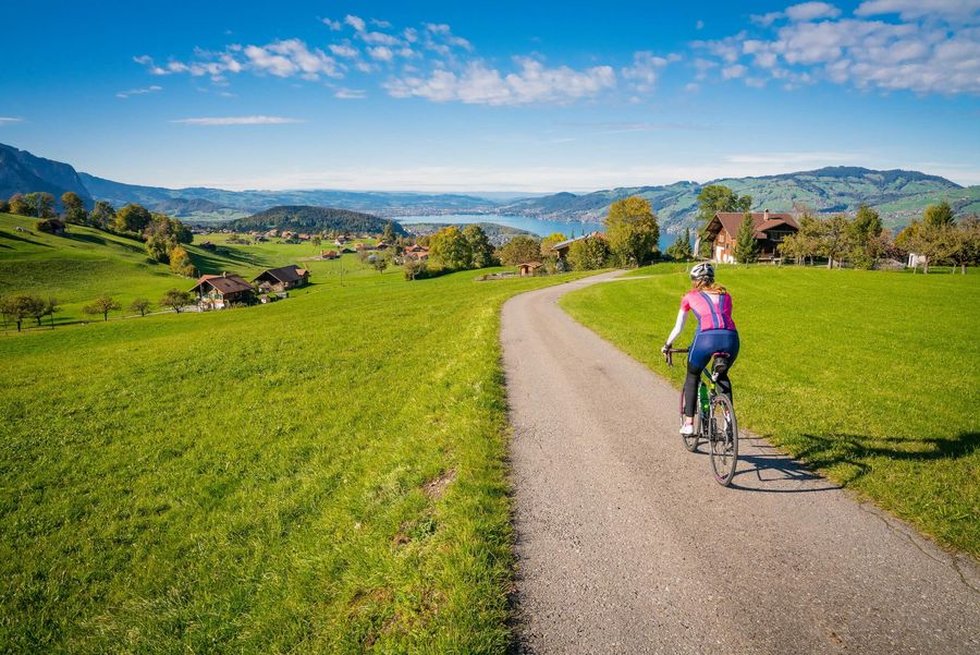 Velofahrerin mit Rennrad unterwegs in Aeschi umgeben von grünen Wiesen