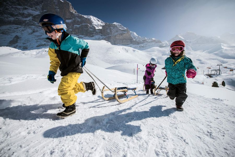 Kinder mit Schlitten im Schnee auf dem Eiger Run Schlittelweg im Winter