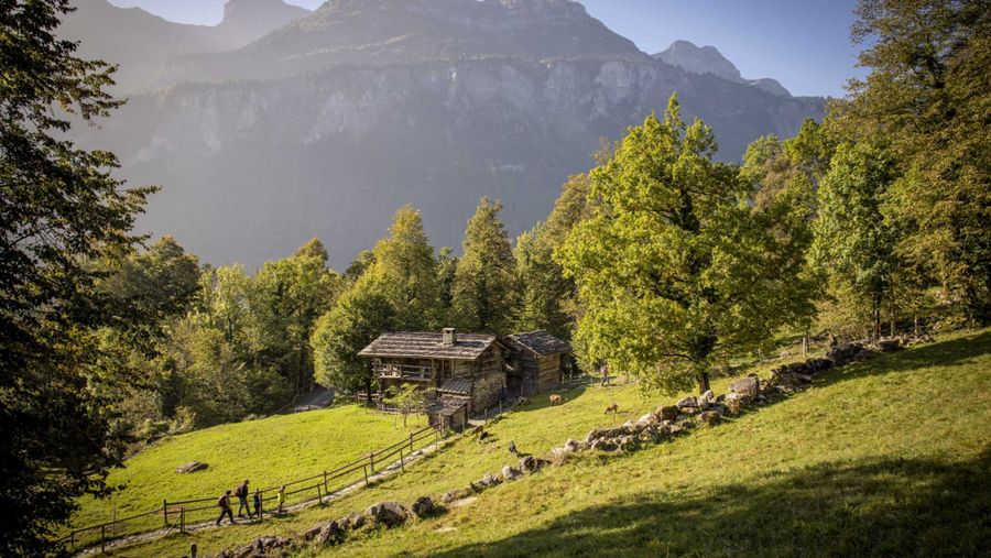 Besucher unterwegs im Freilichtmuseum Ballenberg, im Hintergrund ist die Oltschiburg (Berg) zu sehen.