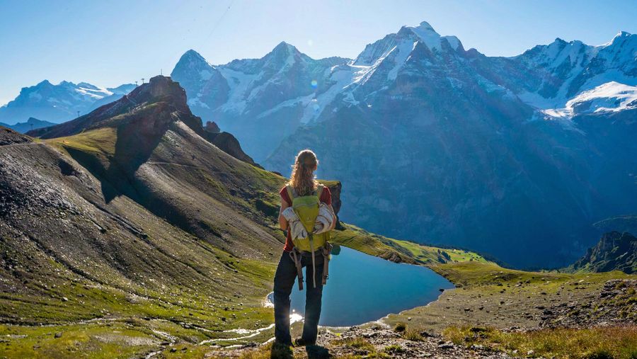 Eine Wandererin blickt auf das Grauseeli, im Hintergrund die Station Birg