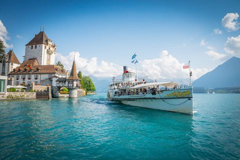 Märchenhaftes Schloss Oberhofen mit Dampfschiff Blümlisalp, das über den Thunersee gleitet. Im Hintergrund der Niesen.