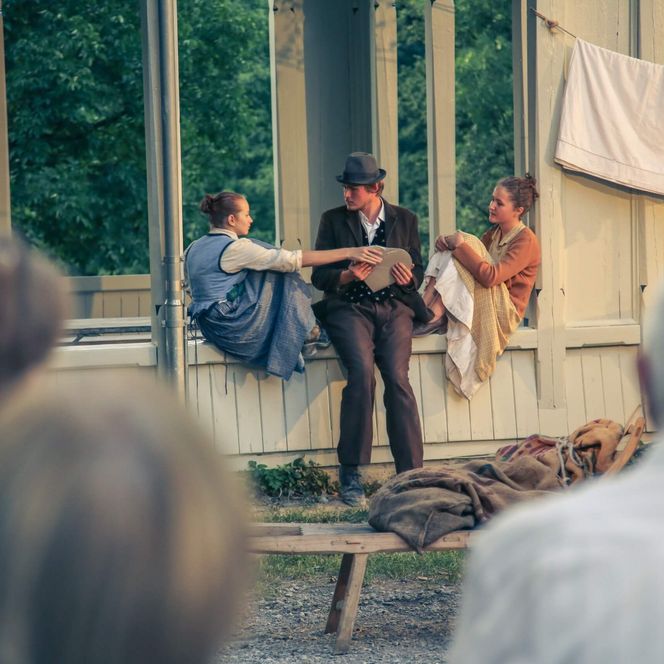 Schauspieler zwischen zwei Schauspielerinnen wird ein Herz überreicht