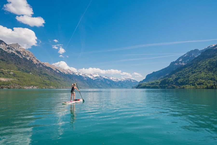 Frau auf einem Stand Up Paddle auf dem türkisen Brienzersee im Frühling
