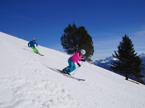 Zwei Skifahrer fahren auf der Piste am Niederhorn
